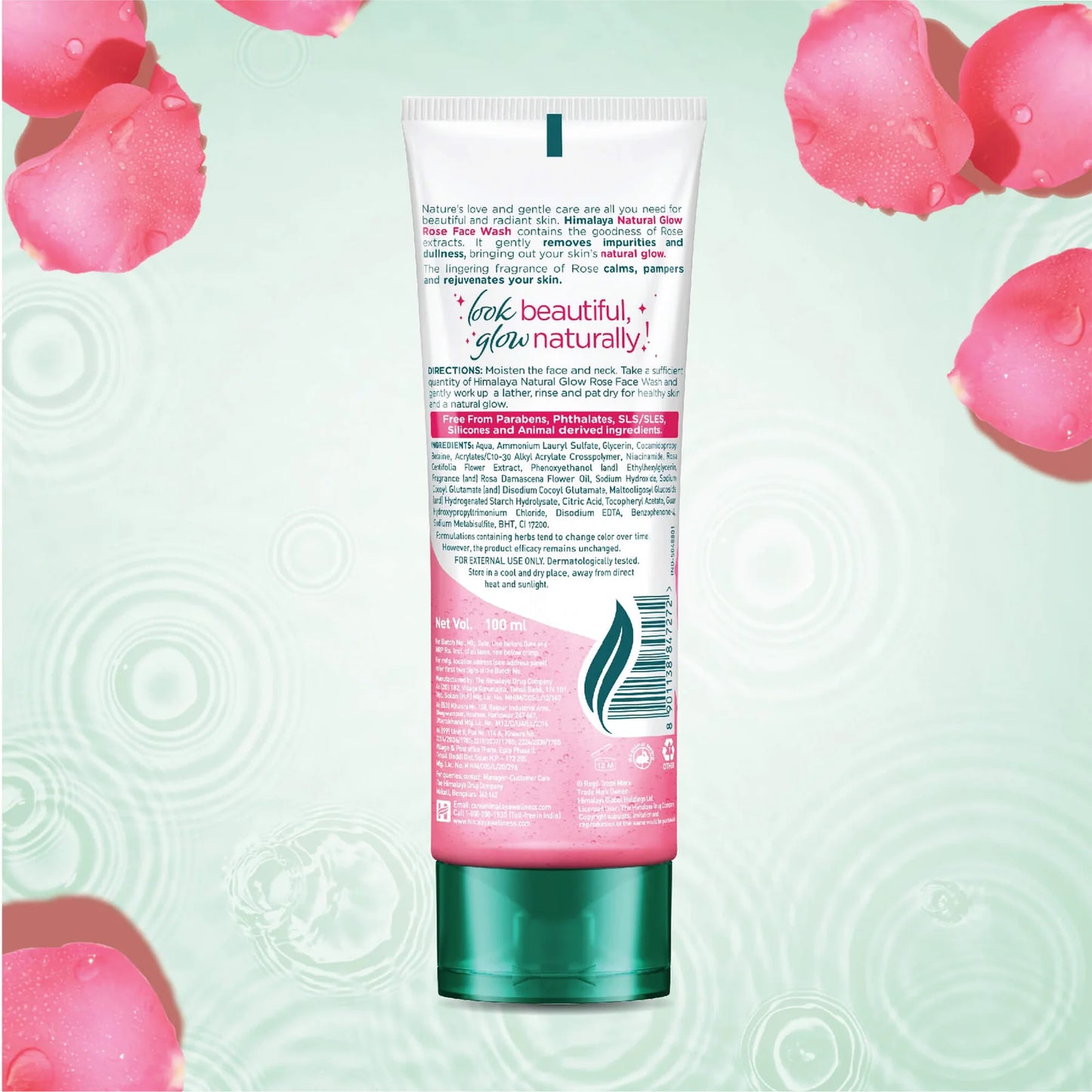 Tube of facial wash with pink label on a light green background with pink rose petals