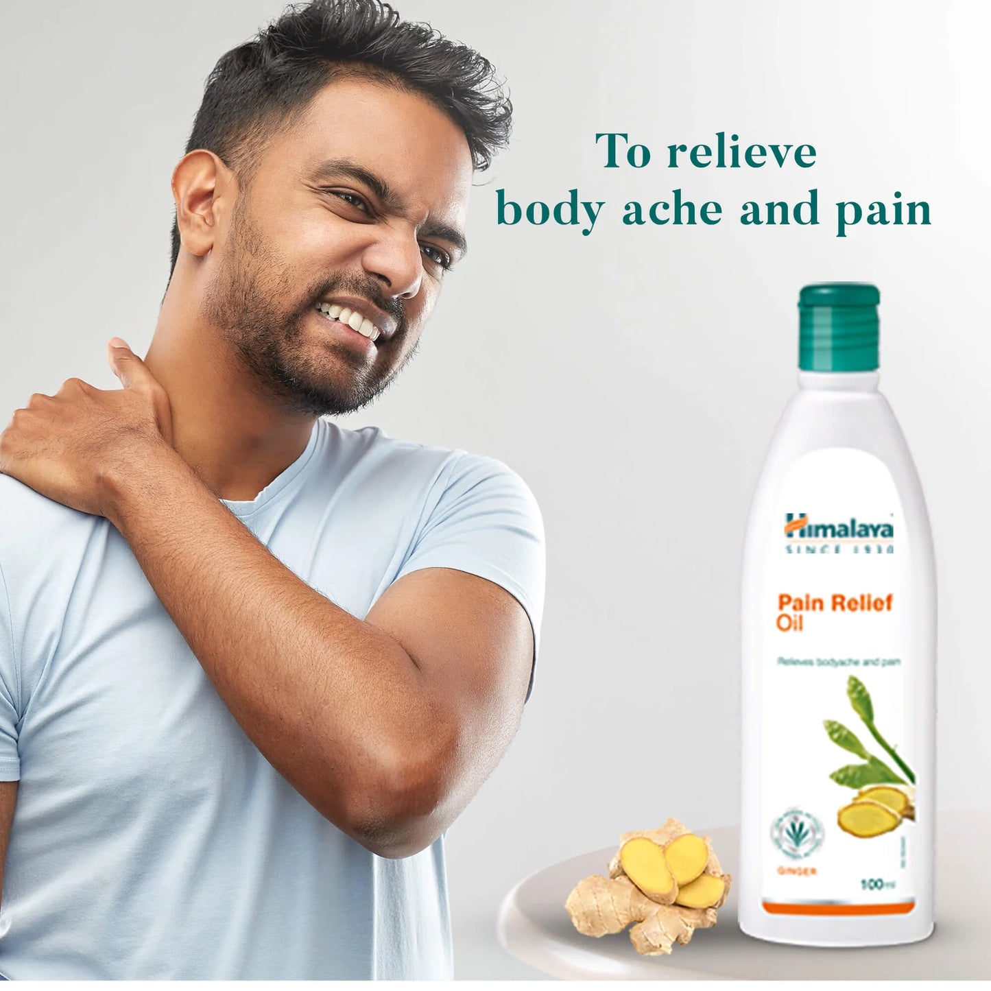 Man with body ache holding shoulder next to Himalaya Pain Relief Oil bottle