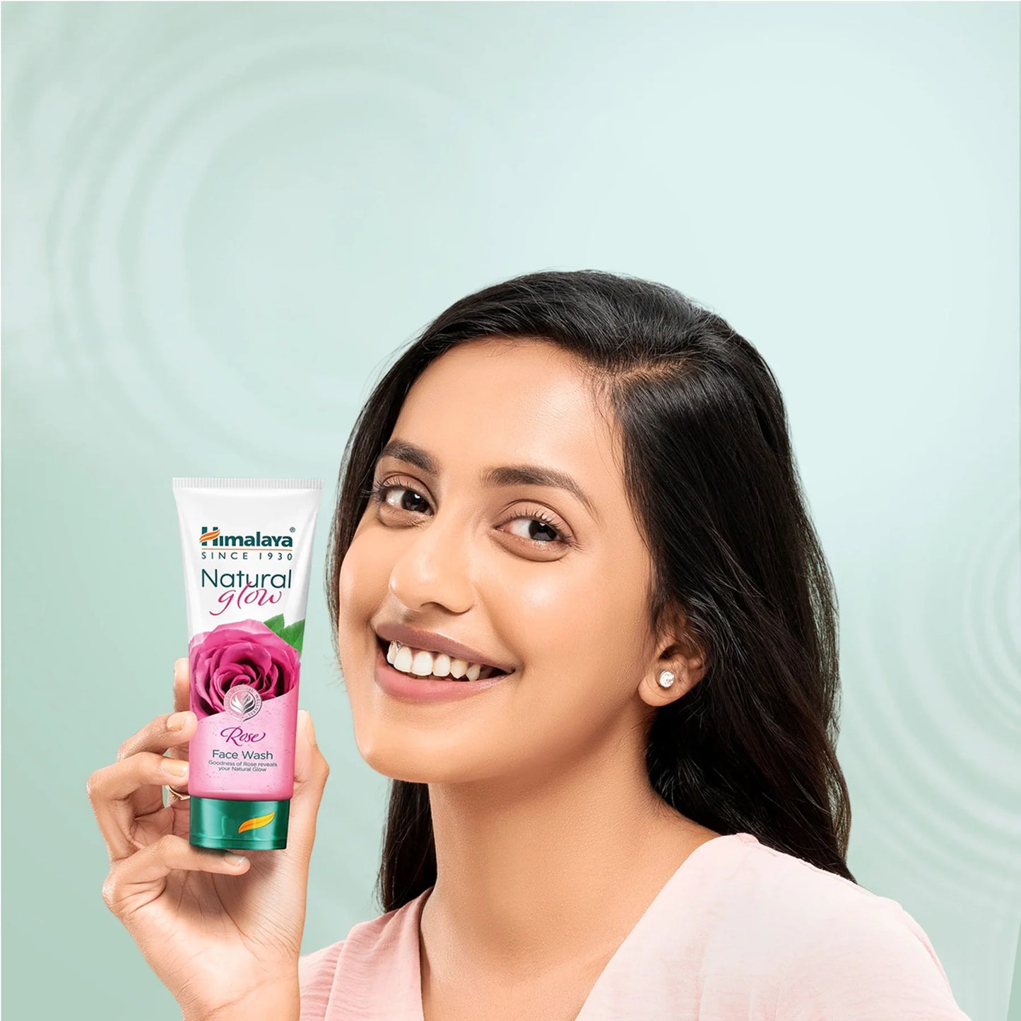 Woman holding a Himalaya Herbals Natural Glow Rose Face Wash against a light green background