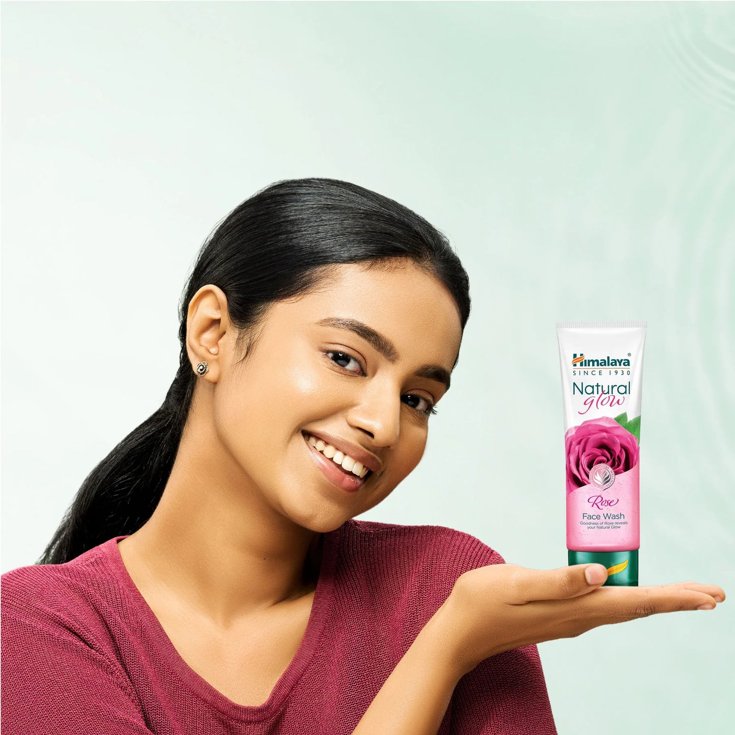 Woman holding a Himalaya Herbals product against a light green background